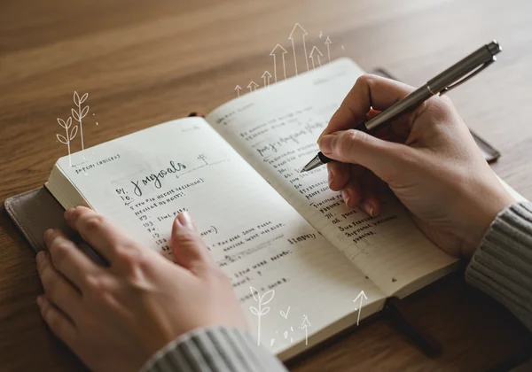 Hand writing in a journal, setting personal growth goals